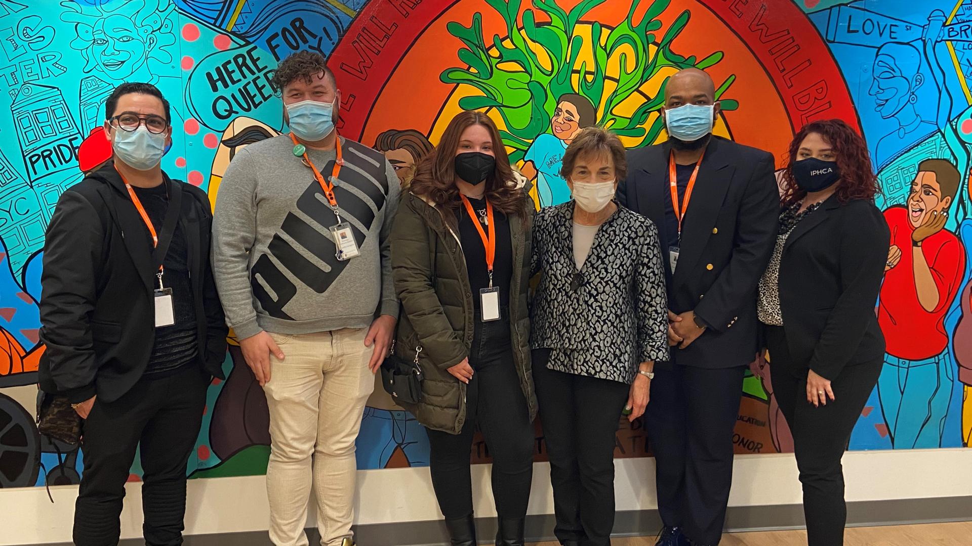 Schakowsky stands with staff at the Broadway Youth Center in front of artwork
